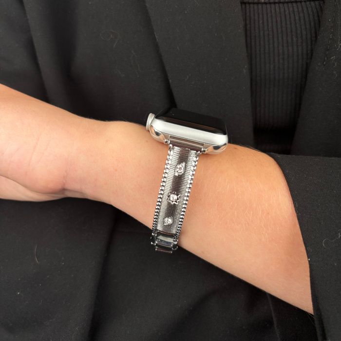 Silver Coconut Lane Shimmer Star Apple Watch strap worn with a sleek black outfit.
