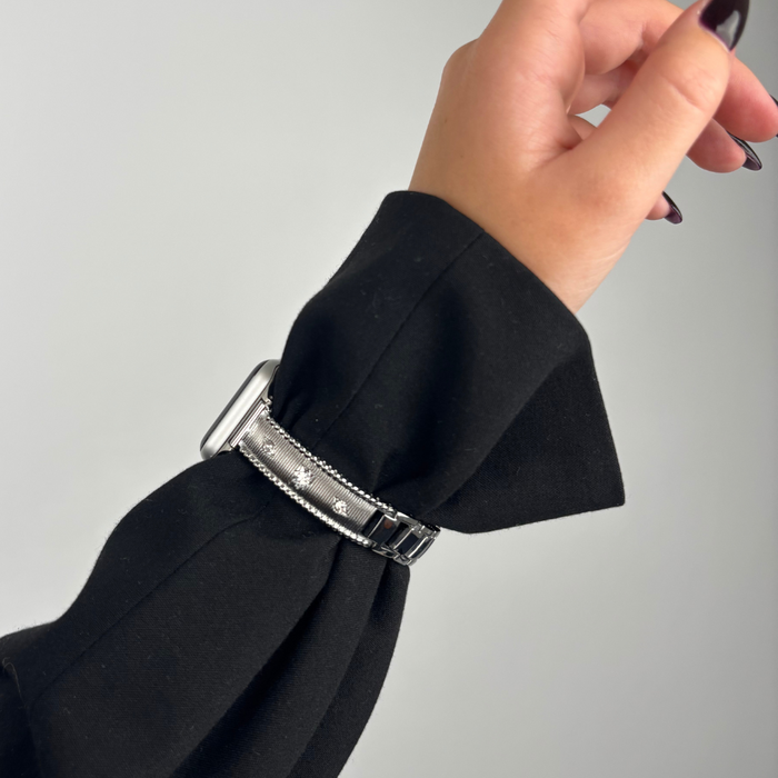 Silver Coconut Lane Shimmer Star Apple Watch strap on wrist with dark nails, shown over a black sleeve.