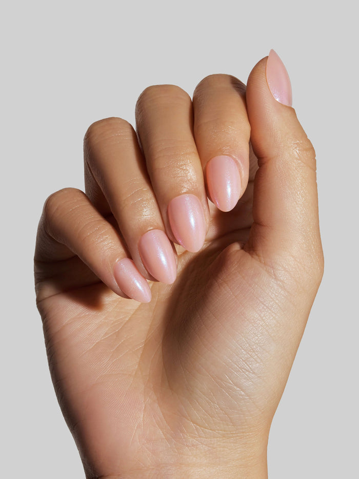 Close-up of a hand with pink press-on nails on a neutral background