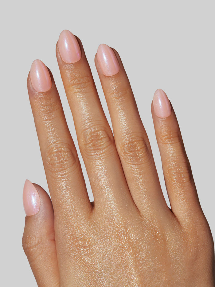 Hand with light pink nail polish on a neutral background