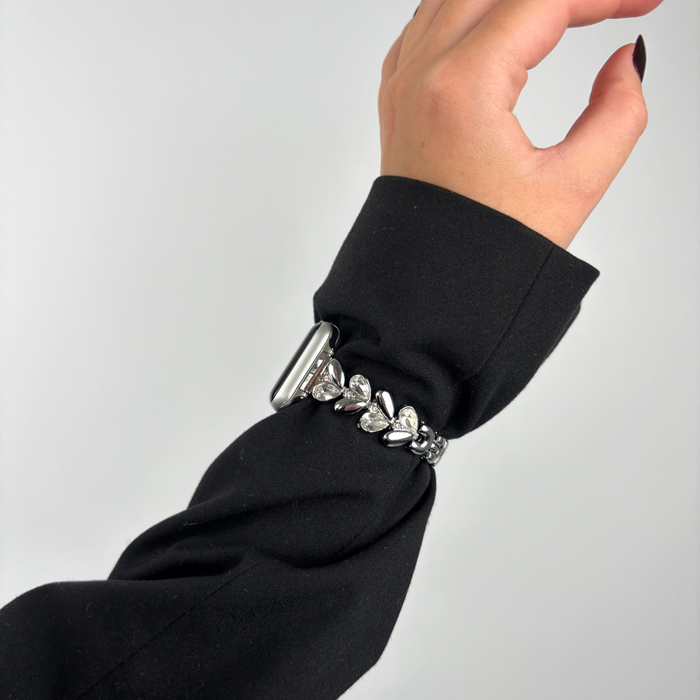 Silver Sparkle Petal Apple Watch strap on wrist, worn with a black sleeve.