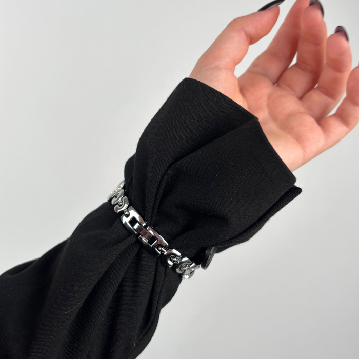 Silver Sparkle Petal Apple Watch strap on wrist with long black nails and a black sleeve.