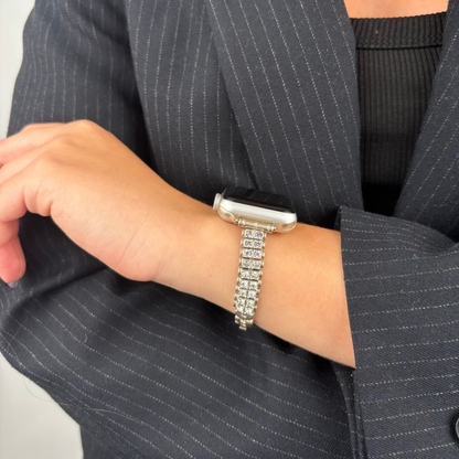 Silver Coconut Lane Sparkle Season Apple Watch strap on a left wrist, paired with a pinstripe blazer.