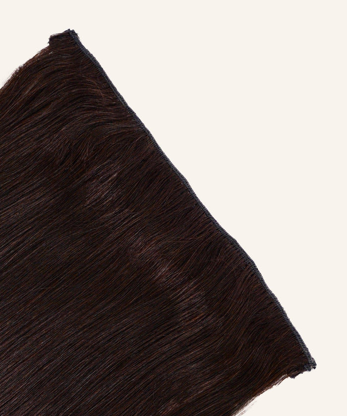 A close-up of Straight Perfect Crown Hair Extensions by Perfect Locks in Honey Blonde , with a sewn weft at the top, on a plain light background.#color_natural-black-(1B)
