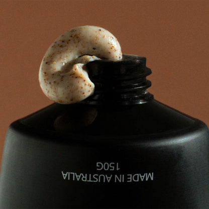 Black bottle cap with gritty textured cream on a brown background.