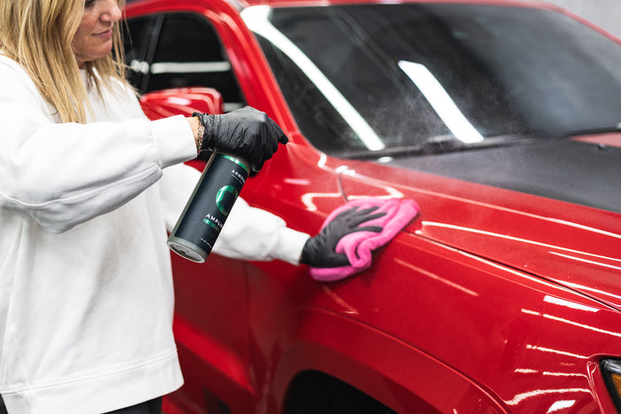 Person applying Armour Detail Amplify to a red car with a pink microfiber towel.