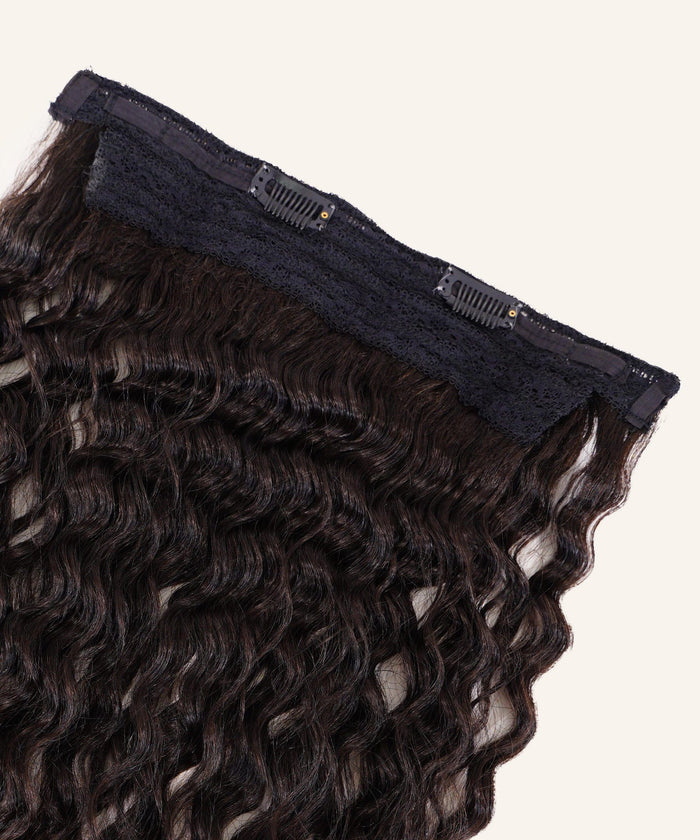 Close-up of Tight Curly Perfect Crown Hair Extensions by Perfect Locks, natural black, with black lace and small clips on beige background.#color_natural-black-(1B)