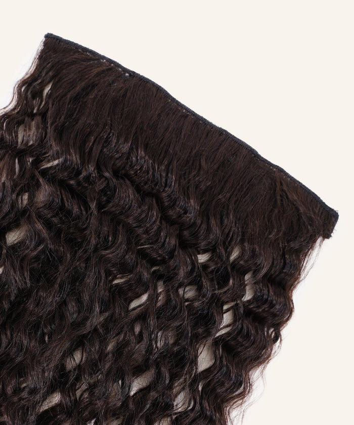 A close-up of Tight Curly Perfect Crown Hair Extensions by Perfect Locks in natural black, with defined curls and wavy Remy hair.#color_natural-black-(1B)