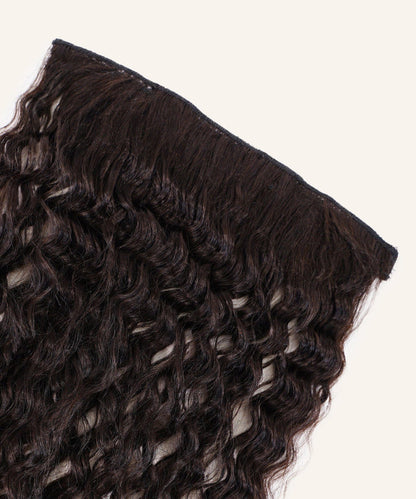 A close-up of Tight Curly Perfect Crown Hair Extensions by Perfect Locks in natural black, with defined curls and wavy Remy hair.#color_natural-black-(1B)