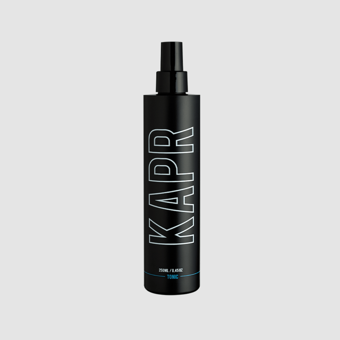 KAPR Tonic – zwarte fles met wit logo op grijze achtergrond, professionele barbershop tonic.