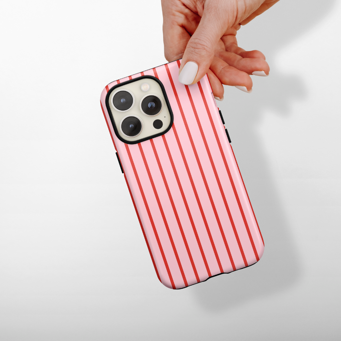Hand holding a Coconut Lane tough phone case with red cherry stripes pattern, shown against a white background.