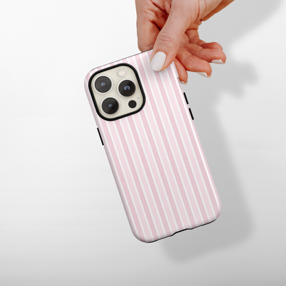 Hand holding smartphone with Coconut Lane Tough Phone Case in pastel powder stripes, plain light background.