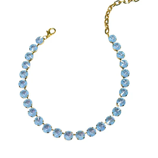 A gold-tone chain necklace featuring a curved row of light blue faceted rhinestones, complete with a lobster clasp and extension chain, shown against a plain white background.