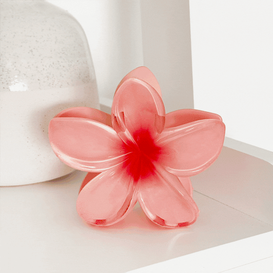 Tropical flower claw clips in bright colors displayed next to a speckled vase and other hair accessories.