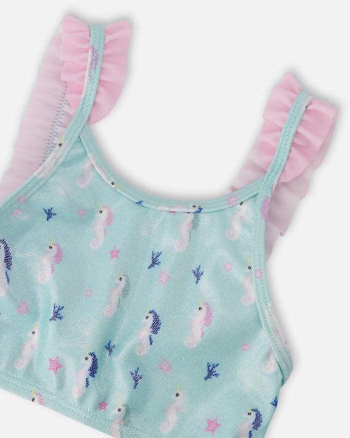 Closeup of Deux par Deux girls swim top showing frilled straps, blue fabric, and seahorse print.