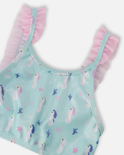 Closeup of Deux par Deux girls swim top showing frilled straps, blue fabric, and seahorse print.